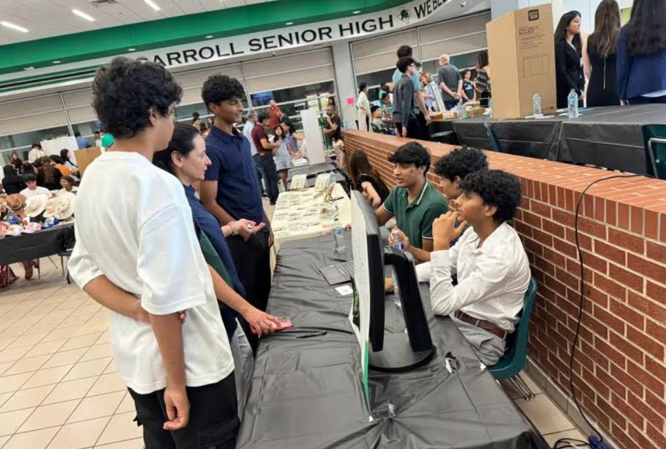 ElderTech students at their table talking with visitors in the Carroll Senior High cafeteria